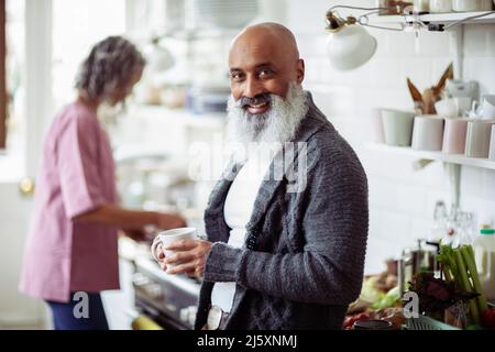 Portrait glücklich reifen Mann mit Bart trinken Kaffee in der Küche Stockfoto