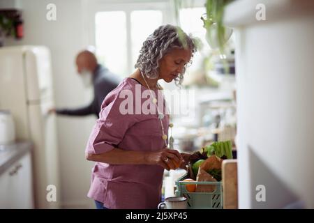 Ältere Frau, die Lebensmittel in der Küche auslädt Stockfoto