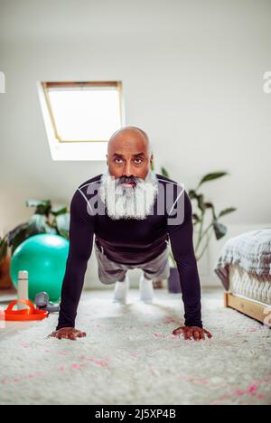 Fokussierter reifer Mann trainieren in Plank Pose auf Schlafzimmer Boden Stockfoto