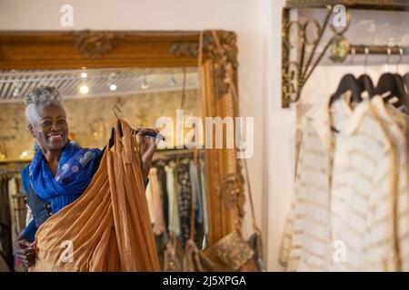 Portrait glückliche ältere Frau, die in der Bekleidungsboutique einkauft Stockfoto