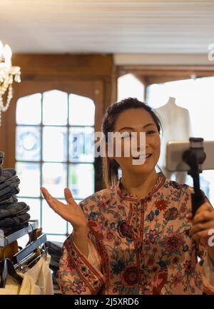 Weibliche Ladenbesitzerin vloggt mit Smartphone in der Boutique Stockfoto