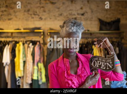 Portrait selbstbewusste ältere weibliche Ladenbesitzerin mit offenem Schild Stockfoto