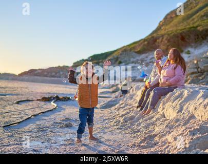 Glücklicher Junge mit Down-Syndrom, der am Sandstrand mit Blasen spielt Stockfoto