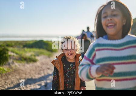 Portrait niedlicher Junge mit Down-Syndrom am Strand mit Familie