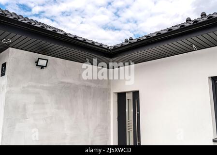 An den Traversen, sichtbaren Kabeln und Löchern für LED-Leuchten ist eine moderne Graphit-Dachverkleidung angebracht. Stockfoto