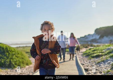 Portrait sorgloser Junge mit Down-Syndrom läuft auf der Strandpromenade Stockfoto