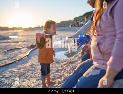 Netter Junge mit Down-Syndrom Blasen am Strand Stockfoto