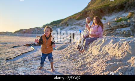 Netter Junge mit Down-Syndrom, der am Strand mit Blasen spielt Stockfoto