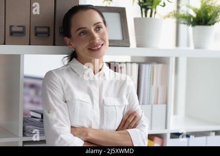 Geschäftsfrau in weißen Blusen, die neben einem Regal mit Ordnern stehen Stockfoto