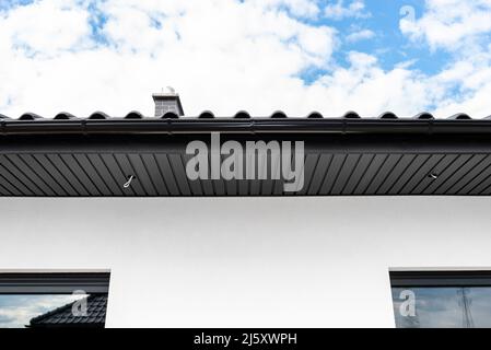 An den Traversen, sichtbaren Kabeln und Löchern für LED-Leuchten ist eine moderne Graphit-Dachverkleidung angebracht. Stockfoto