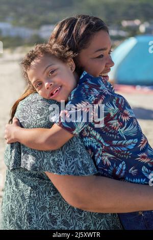 Portrait glücklicher Junge mit Down-Syndrom auf der Schulter der Mutter Stockfoto