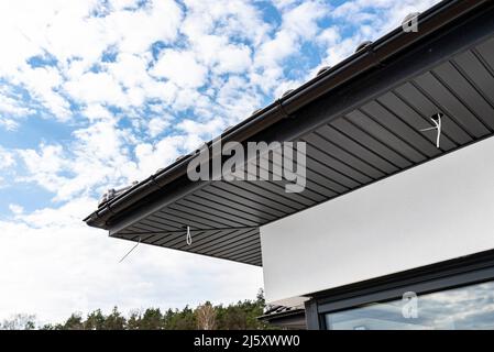 An den Traversen, sichtbaren Kabeln und Löchern für LED-Leuchten ist eine moderne Graphit-Dachverkleidung angebracht. Stockfoto