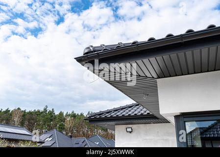 An den Traversen, sichtbaren Kabeln und Löchern für LED-Leuchten ist eine moderne Graphit-Dachverkleidung angebracht. Stockfoto