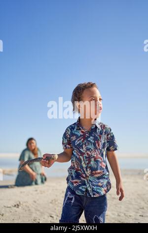 Junge mit Down-Syndrom hält Stock an sonnigen Strand Stockfoto