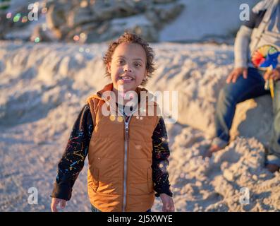 Porträt niedlichen Jungen mit Down-Syndrom beobachten Blasen am Strand