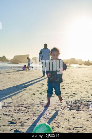 Sorgloser Junge mit Down-Syndrom, der am sonnigen Strand spielt Stockfoto
