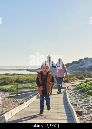 Glücklicher Junge mit Down-Syndrom, der auf der Strandpromenade läuft Stockfoto