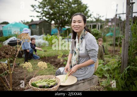 Portrait glückliche Frau, die im Garten Butterbohnen erntet Stockfoto