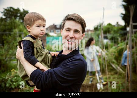 Portrait glücklicher Vater und Kleinkind Sohn im Garten Stockfoto