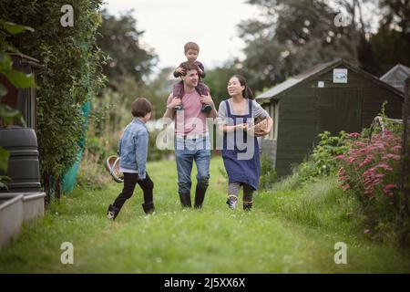 Glückliche Familie, die im Gras im Garten im Hinterhof spazieren geht Stockfoto