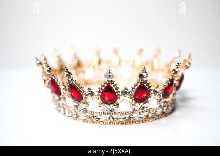 Eine Replik einer goldenen Krone, die mit roten und weißen Diamanten auf weißem Grund isoliert ist. Diadem. Stockfoto