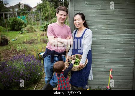 Portrait glückliche Familie mit geerntetem Gemüse im Garten Stockfoto