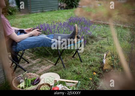 Mann, der sich im Garten mit geerntetem Gemüse entspannt Stockfoto