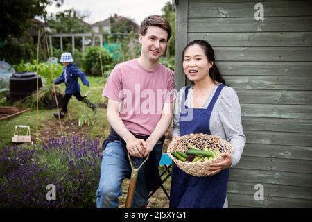 Portrait glückliches Paar mit geerntetem Gemüse im Garten Stockfoto