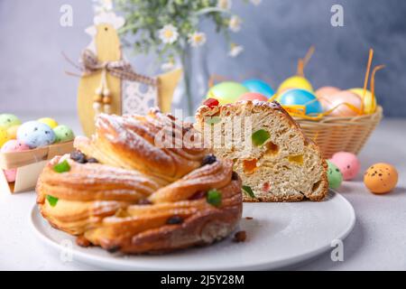 Cutaway Craffin (Cruffin) mit Rosinen und kandierten Früchten. Traditionelles Osterbrot Kulich und bemalte Eier auf grauem Hintergrund. Osterferien. Clos Stockfoto