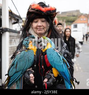 WHITBY, ENGLAND. April 24. 2022. Inhaber von Parrots & Pirates Ltd, der zwei Papageien hält, wird am Goth-Wochenende auf der Bridge Street in Whitby gesehen. Stockfoto