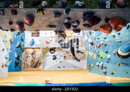 Weibliche Klettererin, die an einer Felswand hängt Stockfoto
