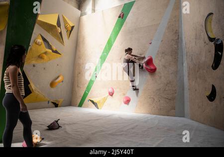 Frau, die einen Freund an der Kletterwand beobachtet Stockfoto