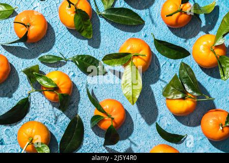 Draufsicht Vollbildhintergrund von reifen tropischen Mandarinen mit Blättern Scheiben und Haut auf gerissenen hellblauen Oberfläche Stockfoto