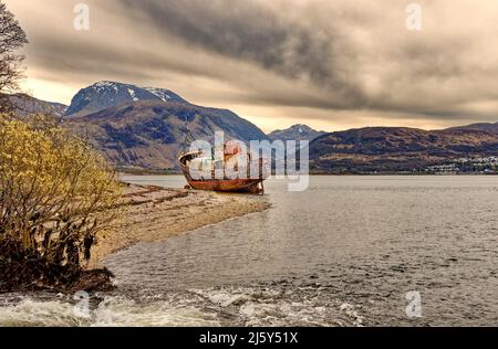 FORT WILLIAM SCOTLAND CAOL KIESSTRAND UND DAS GESTRANDETE VERALTETE ALTE FISCHERBOOT Stockfoto