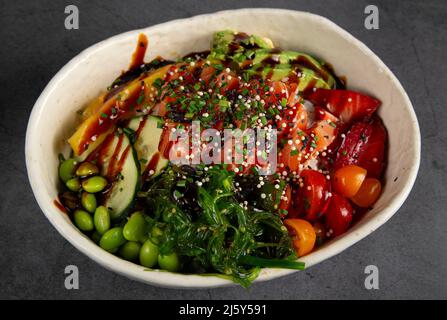 Von oben servieren wir eine leckere Schüssel mit Edamame-Bohnen und grünen chuka-Salat mit gehackten Kirschtomaten und Gurkenscheiben mit Sesamsamen Stockfoto