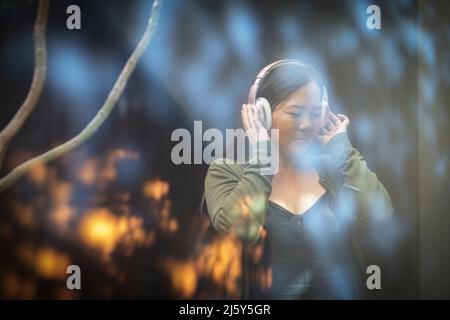 Eine ruhige Frau, die mit Kopfhörern Musik hört Stockfoto