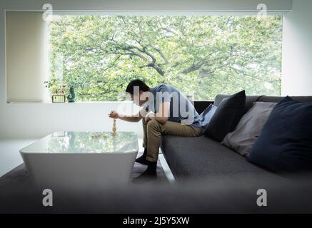 Mann stapelt Steine auf einem modernen Couchtisch im Wohnzimmer Stockfoto