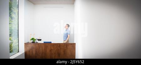Nachdenklicher männlicher Ingenieur, der im Büro hinter dem Schreibtisch steht Stockfoto