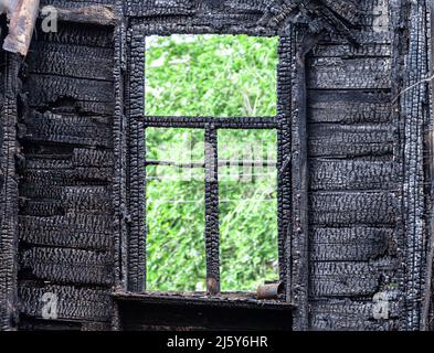Verkohlte hölzerne Fensterrahmen eines ausgebrannten Hauses Stockfoto