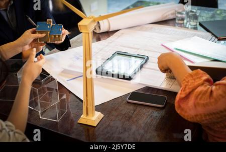 Architekten und Ingenieure mit Blick auf Baupläne und Hausmodell Stockfoto