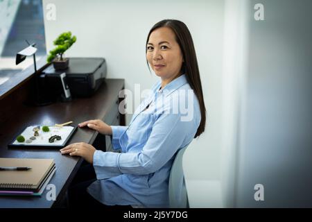 Portrait Geschäftsfrau mit Zen-Garten im Büro Stockfoto