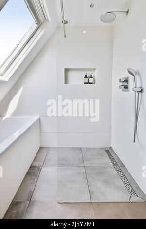 Dusche vor einer Badewanne im hellen Dachgeschoss-Badezimmer Stockfoto