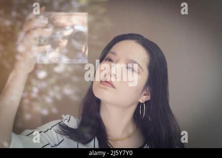 Kreative junge Geschäftsfrau, die Würfel mit Wasser hält Stockfoto