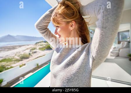 Sorglose junge Frau auf der Terrasse des sonnigen Sommerstrandhauses Stockfoto