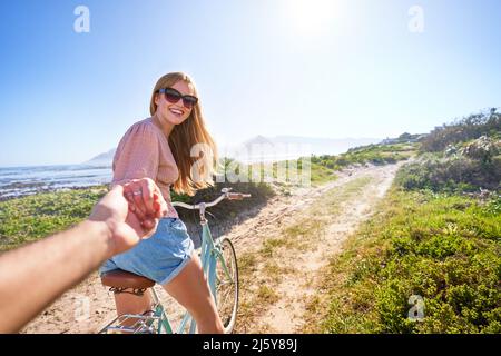 POV glückliche Freundin auf dem Fahrrad auf sonnigen Sommer Strandweg Stockfoto