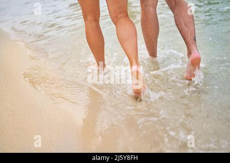 Beine eines Paares, das in der Meeresbrandung läuft Stockfoto