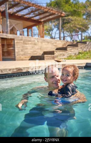 Portrait glücklicher Vater und Kleinkind Sohn im Schwimmbad Stockfoto