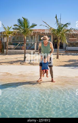 Vater und niedlicher Kleinkind Sohn spielen im sonnigen Sommer Ozean Stockfoto