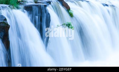 Die Landschaft des TAD Pha Suam Wasserfalls in der Regenzeit, Süßwasser fließt aus dem Felsvorsprung, Reiseziele in Süd-Laos. Stockfoto