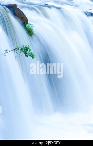 Die Landschaft des TAD Pha Suam Wasserfalls in der Regenzeit, Süßwasser fließt aus dem Felsvorsprung, Reiseziele in Süd-Laos. Stockfoto